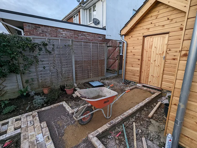 Newly cut paving area outside the garage, with bricks being laid out