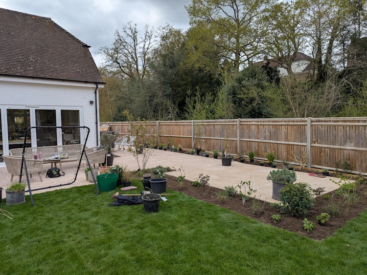 Porcelain patio with integrated planting cut-outs and colourful border plantings along the fence