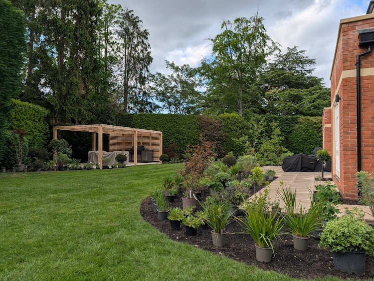 Bespoke timber pergola sheltering an outdoor dining table laid for eight